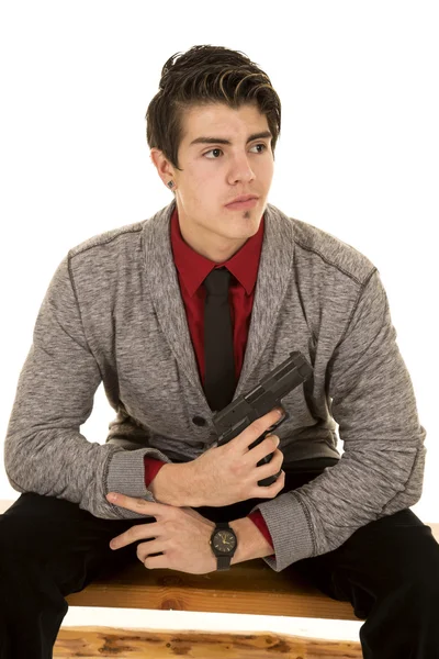 Man in sweater holding gun sitting — Stock Photo, Image