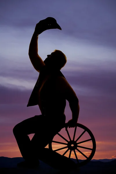 Silhouette of cowboy sitting on wheel — Stock Photo, Image