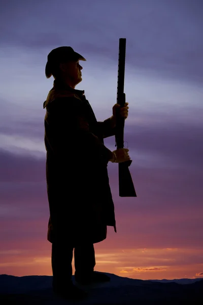 Silhouette eines Cowboys im Mantel mit aufrechtem Gewehr — Stockfoto