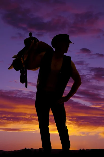 Silhouette of cowboy holding saddle — Stock Photo, Image