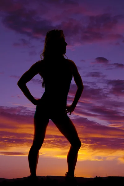 Silhueta de mulher de pé mãos em quadris no pôr do sol — Fotografia de Stock