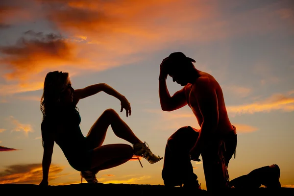 Silhouette di cowboy sul ginocchio e la donna sedersi indietro una gamba in th — Foto Stock