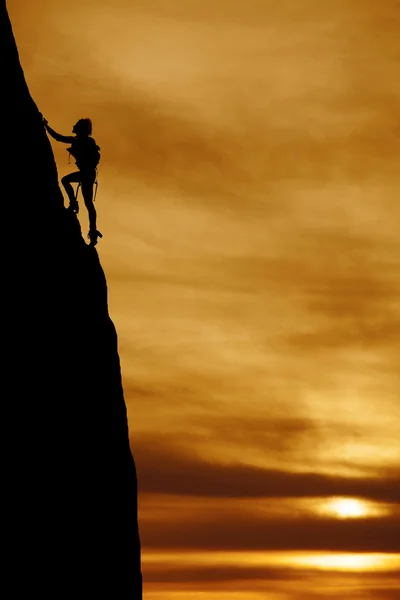 silhouette of woman climbing mountain