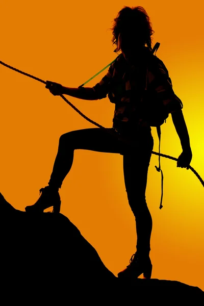 silhouette of woman climbing mountain