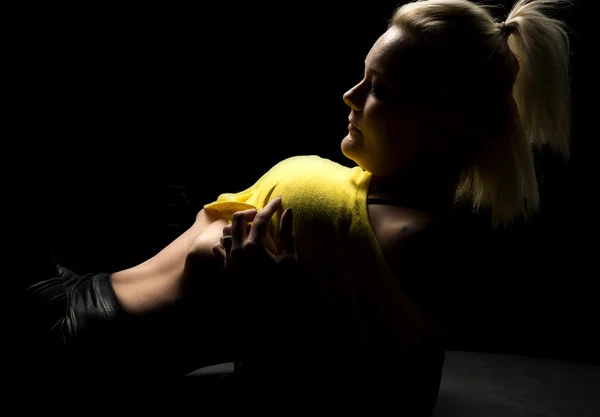Blond woman pull up yellow shirt lay back highlighted — Stock Photo, Image