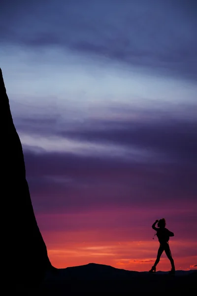 Silhuetten av en kvinna vandrare i solnedgången blickar framåt på mount — Stockfoto