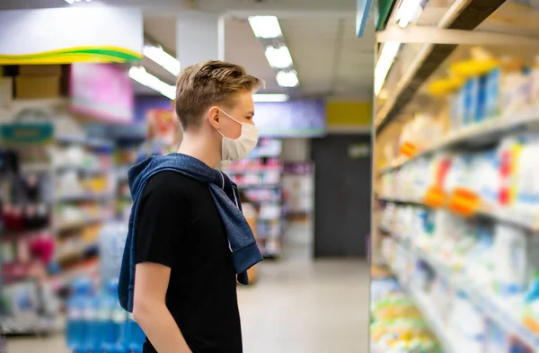 Boy wears protected mask in store. Shopping time during coronavirus outbreak.Boy in a medical mask. Quarantine and protection virus, flu, epidemic COVID-19. Coronavirus quarantine.