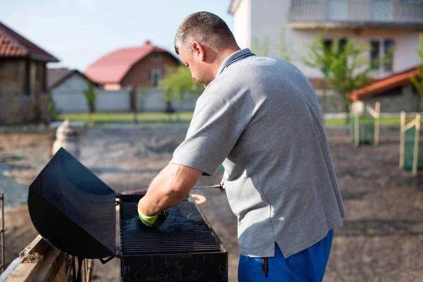 Close-up portrait of a cheerful man grilling meat on barbecue outdoors.