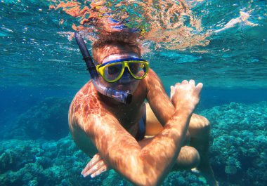 Sualtı çekimi. Tropikal bir denizde dalış yapan bir adam. Seyahat yaşam tarzı, açık deniz sporları macerası, yaz tatilinde yüzme dersleri.