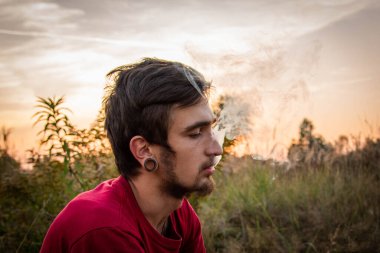 Genç beyaz bir adam dışarıda sigara / ot içiyor. Esrarın yasal olmasını istiyorum.
