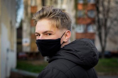 Cerrahi bandajlı tatlı bir genç çocuk. Coronavirus, hastalık, enfeksiyon, karantina, tıbbi maske, COVID-19. Tıbbi maskeli bir çocuk. Karantina ve koruma virüsü, grip, salgın COVID-19.