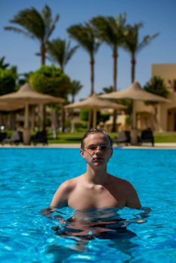 Gerçek insanlar konsepti, güzel genç adam, genç çocuk yüzüyor ve tatilde bilardoda eğleniyor. Tadını çıkaran insanlar için mutluluk ve güzel bir vücut alternatif bir yaşam tarzı.