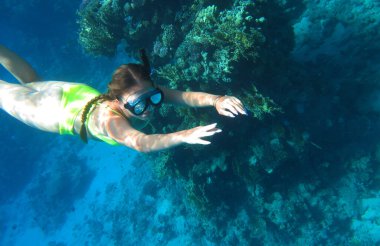 Sualtı çekimi. Tropikal bir denizde tüplü dalış yapan tatlı bir genç kız. Seyahat yaşam tarzı, açık deniz sporları macerası, yaz tatilinde yüzme dersleri.