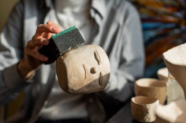 Sanat stüdyosunda işlenmemiş kil şekillendiren genç bir sanatçı. Sanatçının stüdyosundaki kil heykellerden kız kalıpları. Çömlekçisindeki iş kadını.