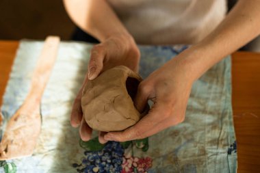 Çömlek. Elinde ip olan bir kız kilin üst katmanını kesiyor. Seramik yazılımı modelleme süreci.