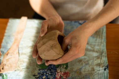 Çömlek. Elinde ip olan bir kız kilin üst katmanını kesiyor. Seramik yazılımı modelleme süreci.