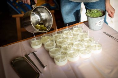 Erimiş balmumunu kehribar mumların içine döken kadın. Ekolojik ve vejetaryen işleri. Soya mumu aksesuarları. Sevgiyle el yapımı. Uzak çalışma, çevrimiçi dükkan, işyeri