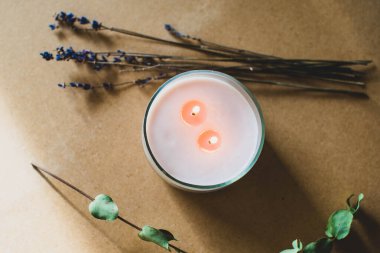 Tahta fitil mumu. Parafinden el yapımı mum ve çiçekli camda soya mumu ve el işi arka planda yaprak. Derisini yüzelim. Mum yapımı. Üst görünüm.