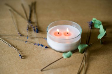 Tahta fitil mumu. Parafinden el yapımı mum ve çiçekli camda soya mumu ve el işi arka planda yaprak. Derisini yüzelim. Mum yapımı. Üst görünüm.