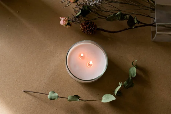 wooden wick candle. Handmade candle from paraffin and soy wax in glass with flowers and leaf on craft background. Let flay. Candle making. Top view.