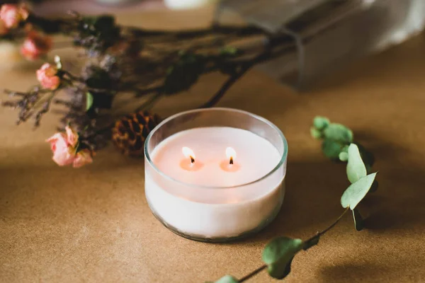 wooden wick candle. Handmade candle from paraffin and soy wax in glass with flowers and leaf on craft background. Let flay. Candle making. Top view.