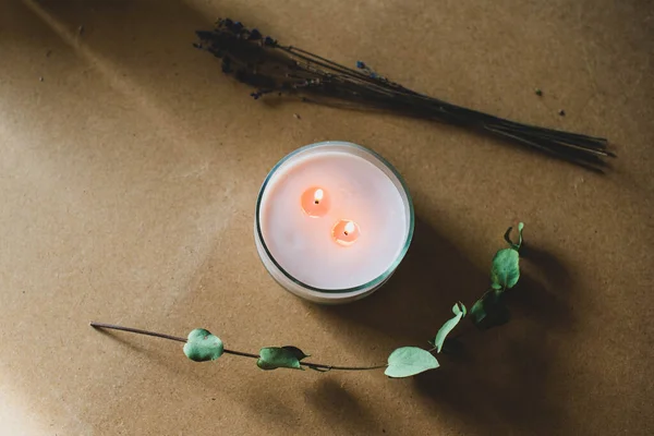 wooden wick candle. Handmade candle from paraffin and soy wax in glass with flowers and leaf on craft background. Let flay. Candle making. Top view.