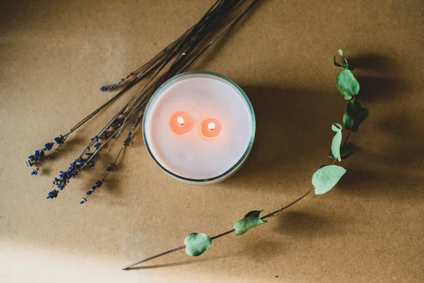 wooden wick candle. Handmade candle from paraffin and soy wax in glass with flowers and leaf on craft background. Let flay. Candle making. Top view.