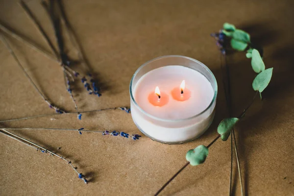 wooden wick candle. Handmade candle from paraffin and soy wax in glass with flowers and leaf on craft background. Let flay. Candle making. Top view.