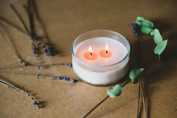 wooden wick candle. Handmade candle from paraffin and soy wax in glass with flowers and leaf on craft background. Let flay. Candle making. Top view.