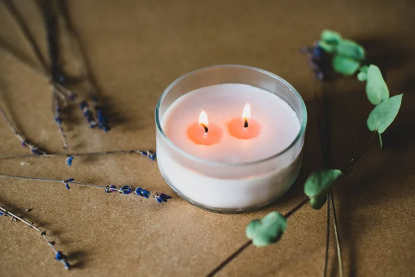 wooden wick candle. Handmade candle from paraffin and soy wax in glass with flowers and leaf on craft background. Let flay. Candle making. Top view.