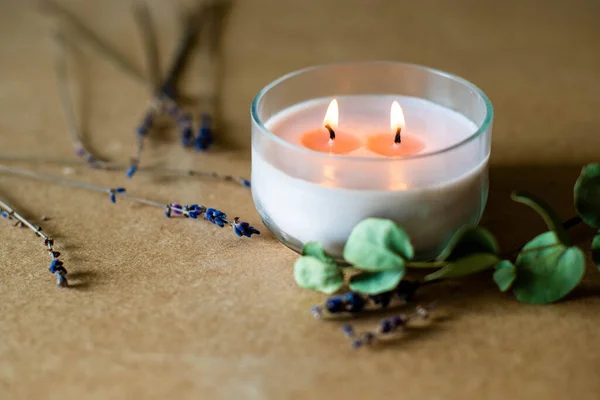 wooden wick candle. Handmade candle from paraffin and soy wax in glass with flowers and leaf on craft background. Let flay. Candle making. Top view.