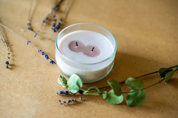 wooden wick candle. Handmade candle from paraffin and soy wax in glass with flowers and leaf on craft background. Let flay. Candle making. Top view. lavender, craft background.