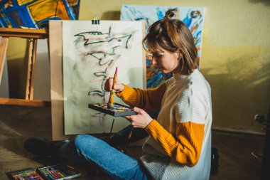 Güzel bir kadın resmi. Resim stüdyosundaki kız. Yetenekli Kadın Sanatçı Modern Soyut Yağlı Boyama, Geniş Vuruşlar Kullanarak Hareketlendirme Boya Fırçası üzerinde çalışıyor. Karanlık Yaratıcı Stüdyo