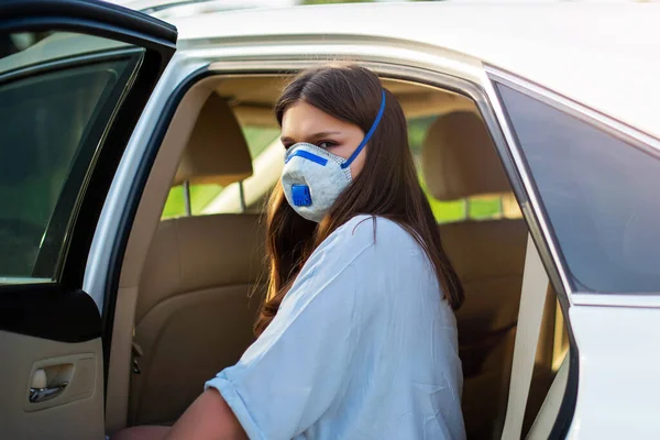 Cute teenage girl in a surgical bandage. Coronavirus, illness, infection, quarantine, medical mask, COVID-19. Girl in a medical mask in car. Quarantine and protection virus, flu, epidemic COVID-19.