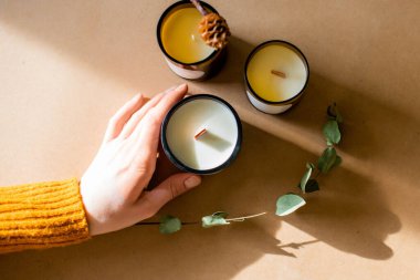 Tahta fitil mumları. Parafinden el yapımı mum ve el işi arka planda yapraklı soya ağdası. Derisini yüzelim. Mum yapımı. Üst Manzara. Kadınların elleri mumları tutuyor.