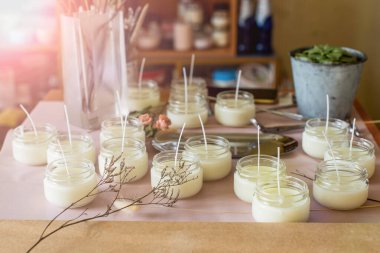 Soya mumları geri dönüşümlü şişe ve kavanozlara döküldü. Mağaza veya atölye arka planında birçok soya mumları birlikte. - Evet. Ekolojik ve vejetaryen işleri.
