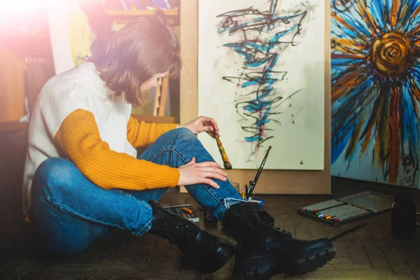 Beautiful woman painting. Girl in Painting Studio. Talented Female Artist Working on a Modern Abstract Oil Painting, Gesturing with Broad Strokes Using Paint Brush. Dark Creative Studio