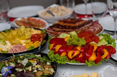 Bardaklar beyaz masada. Masada meyve, tabak ve yemek servisi yapan bir oda. Peynir, bal, salata, atıştırmalık.