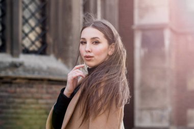 Bulutlu bir günde güneş gözlüklü, uzun kahverengi saçlı genç bir kadın. Modaya uygun seksi kız. Sokak modası görünüşü. Sevimli öğrenci..