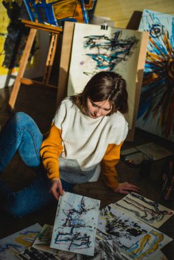 Yaratıcı mutlu ressam renkli bir tablo çizer. Sanat işyerindeki resim sürecinin kapanışı. Gülümseyen pozitif kadın ressam atölyesinde resim yapıyor..