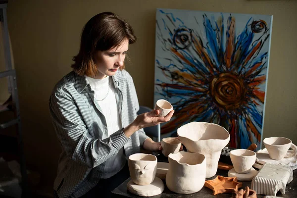 年轻的艺术家在艺术工作室里塑造生粘土 女模特儿是艺术家工作室里的粘土雕塑品 女商人在她的陶器店 — 图库照片