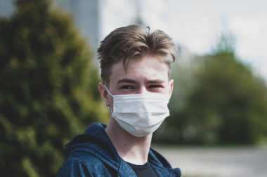 Cerrahi bandajlı tatlı bir genç çocuk. Coronavirus, hastalık, enfeksiyon, karantina, tıbbi maske, COVID-19. Tıbbi maskeli bir çocuk. Karantina ve koruma virüsü, grip, salgın COVID-19.