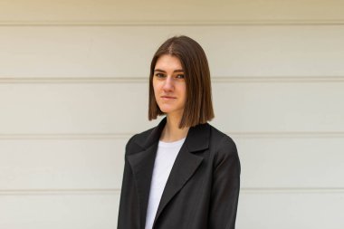 Açık havada iş kadını portresi. İş kıyafetleri içinde genç bir kız özgeçmiş çekimi için poz veriyor..