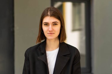 Açık havada iş kadını portresi. İş kıyafetleri içinde genç bir kız özgeçmiş çekimi için poz veriyor..