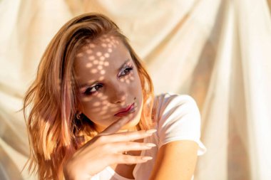 Yüzünde ve vücudunda gölge desenleri olan güzel bir genç kızın portresi. Moda, güzellik, makyaj, kozmetik, güzellik salonu, tarz, kişisel bakım, duruş. Pembe saç. Eğilim