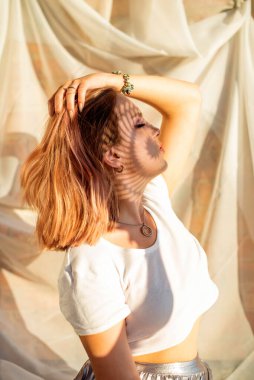 Yüzünde ve vücudunda gölge desenleri olan güzel bir genç kızın portresi. Moda, güzellik, makyaj, kozmetik, güzellik salonu, tarz, kişisel bakım, duruş. Pembe saç. Eğilim