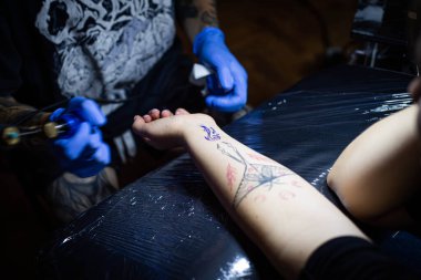 Kuaförde dövmenin kesilip atılmış hali. Profesyonel bir dövme sanatçısı dövme makinesinin iğnesini kullanarak cilde mürekkep yerleştirir. Stüdyoda çalışan profesyonel bir dövmeci..