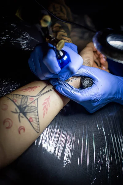 サロンで入れ墨のプロセスの切り取られたショット タトゥーアーティストがタトゥーマシンの針を使って肌にインクを紹介します スタジオで働くプロのタトゥーアーティスト — ストック写真