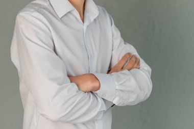 Beyaz gömlekli genç bir adam ve gri arka planda duruyor..