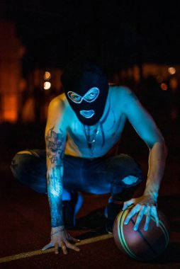 Kar maskeli genç adam kamera suçuna ve şiddete bakıyor, uyuşturucu, moda, rap, rapçi yeni okul, gece kentinde tarz.